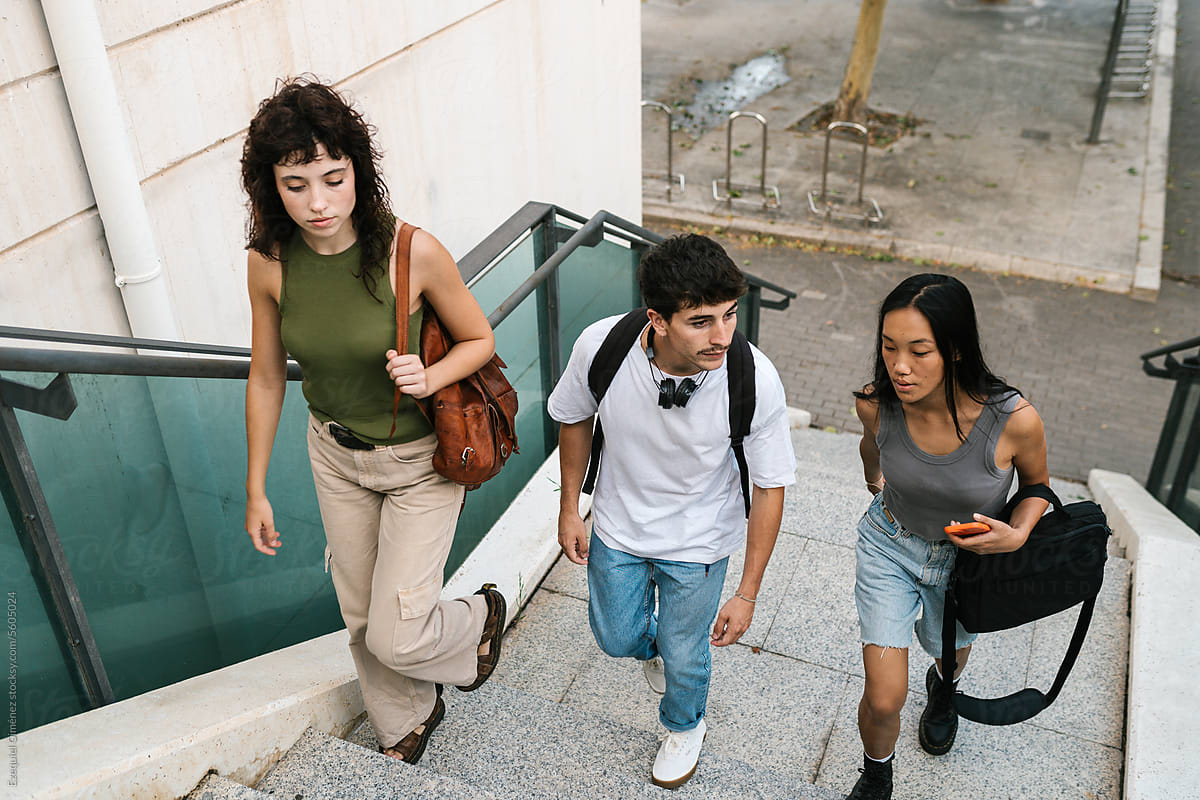 Cheerful diverse young students walking on stairway