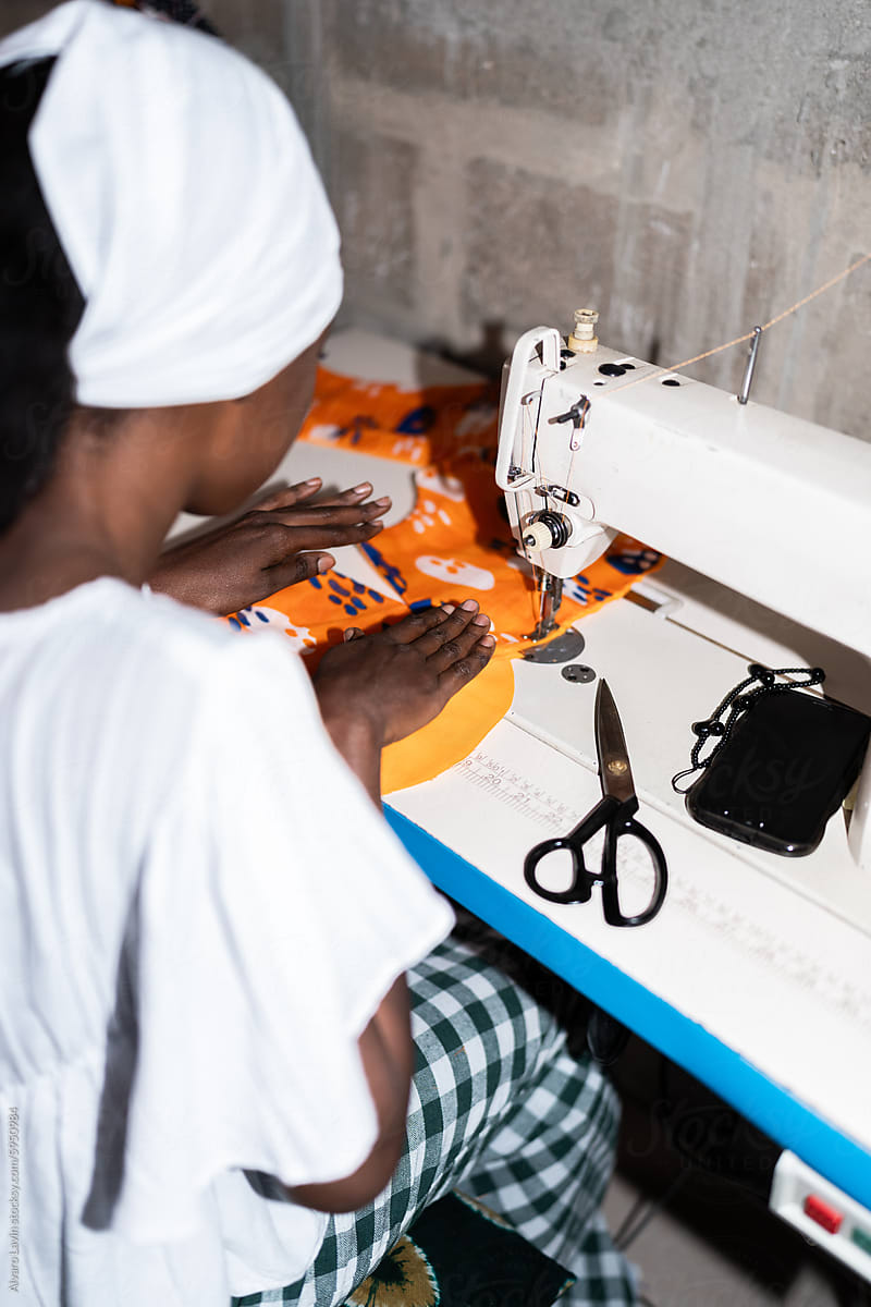 Senegalese Seamstress Concentrating on Sewing Fabric in Her Workshop
