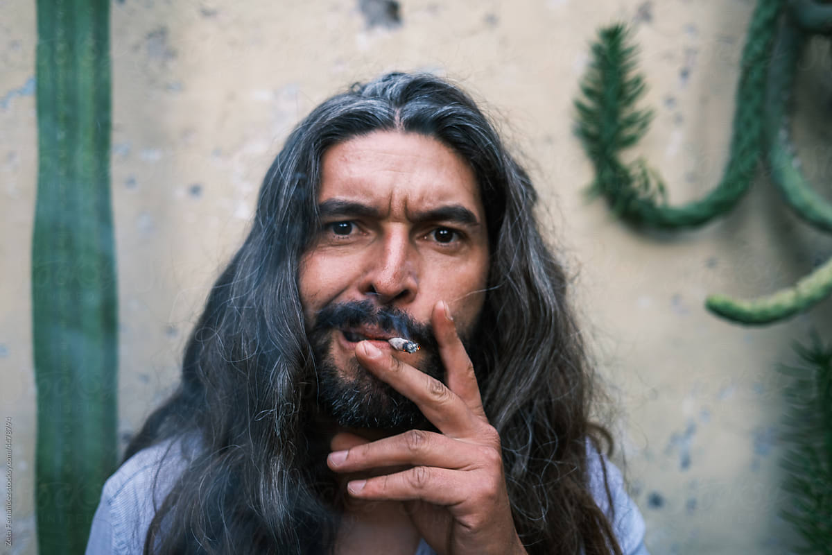portrait of long-haired man with gray hair and beard smoking