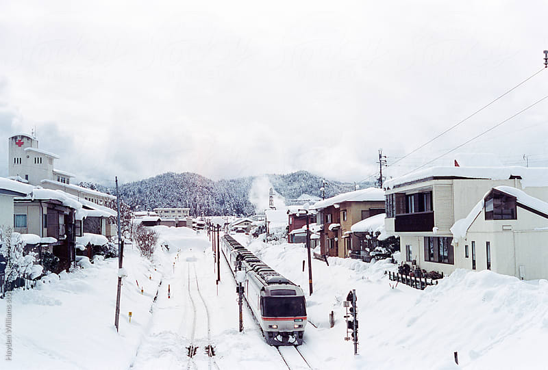 Train going by houses in snow covered Japanese alps