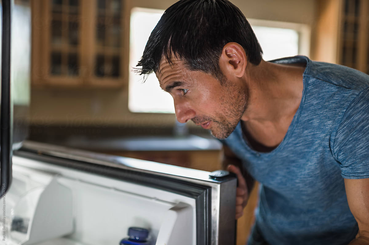 A healthy man examines the refrigerator