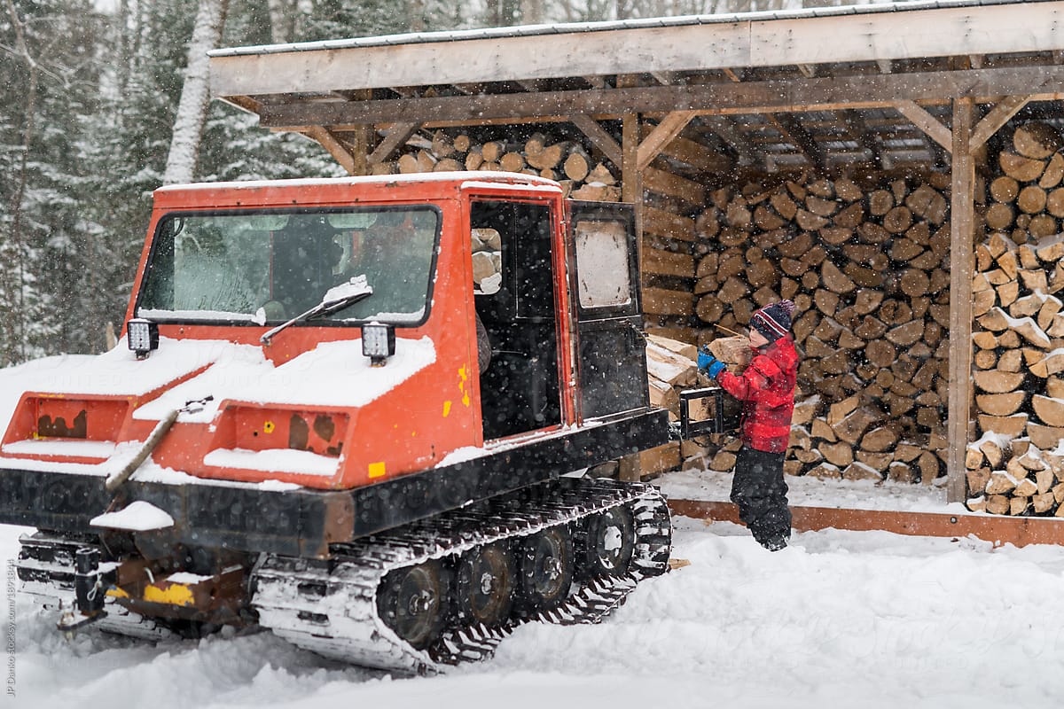 Boy on Muskoka winter vacation helps by gathering firewood onto snow machine