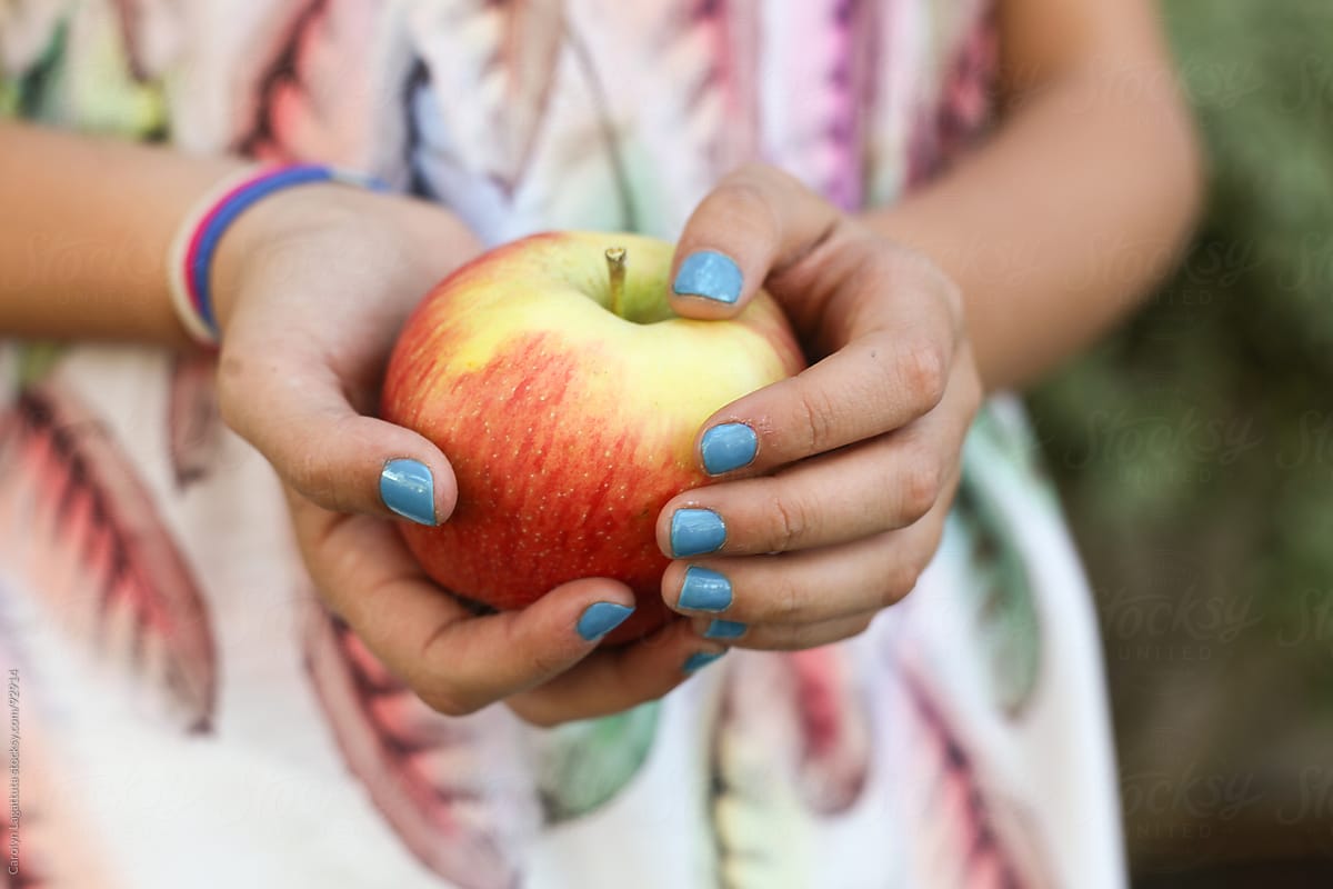 Girl with bright blue nail polish holding an apple