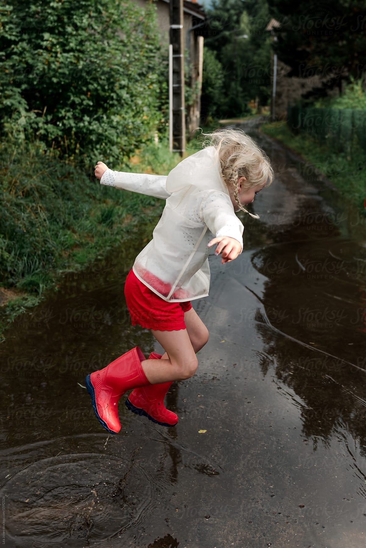 little girl jumping in puddles after the rain