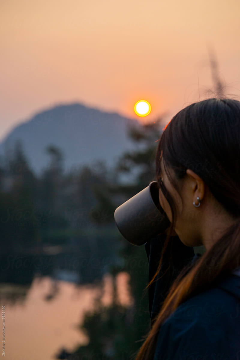 Woman drinking coffee at sunrise