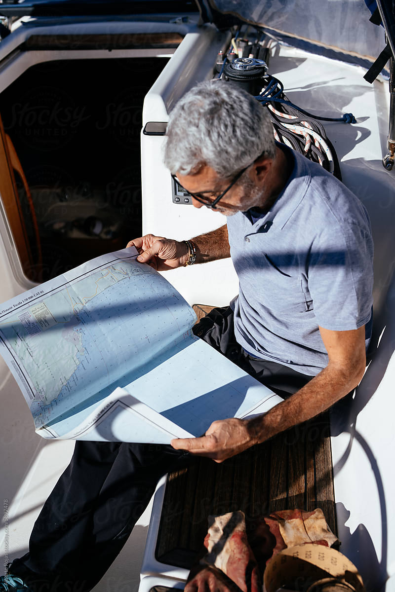 Concentrated senior man reading newspaper on sailboat