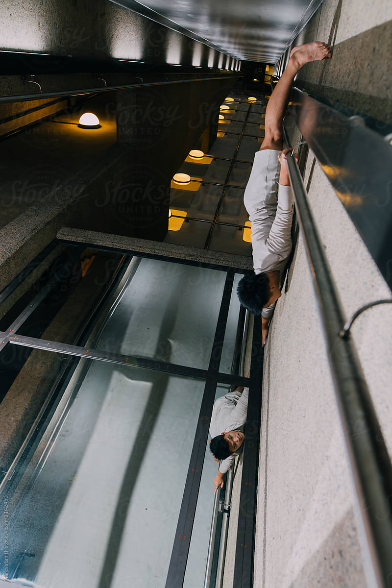 An Asian man appears to be dangling off a concrete ledge towards his reflection