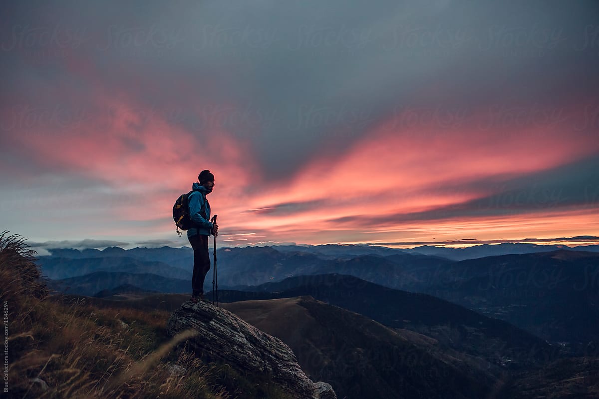 Young man on top of a rocky mountain just in the sunrise moment with the sun glowing