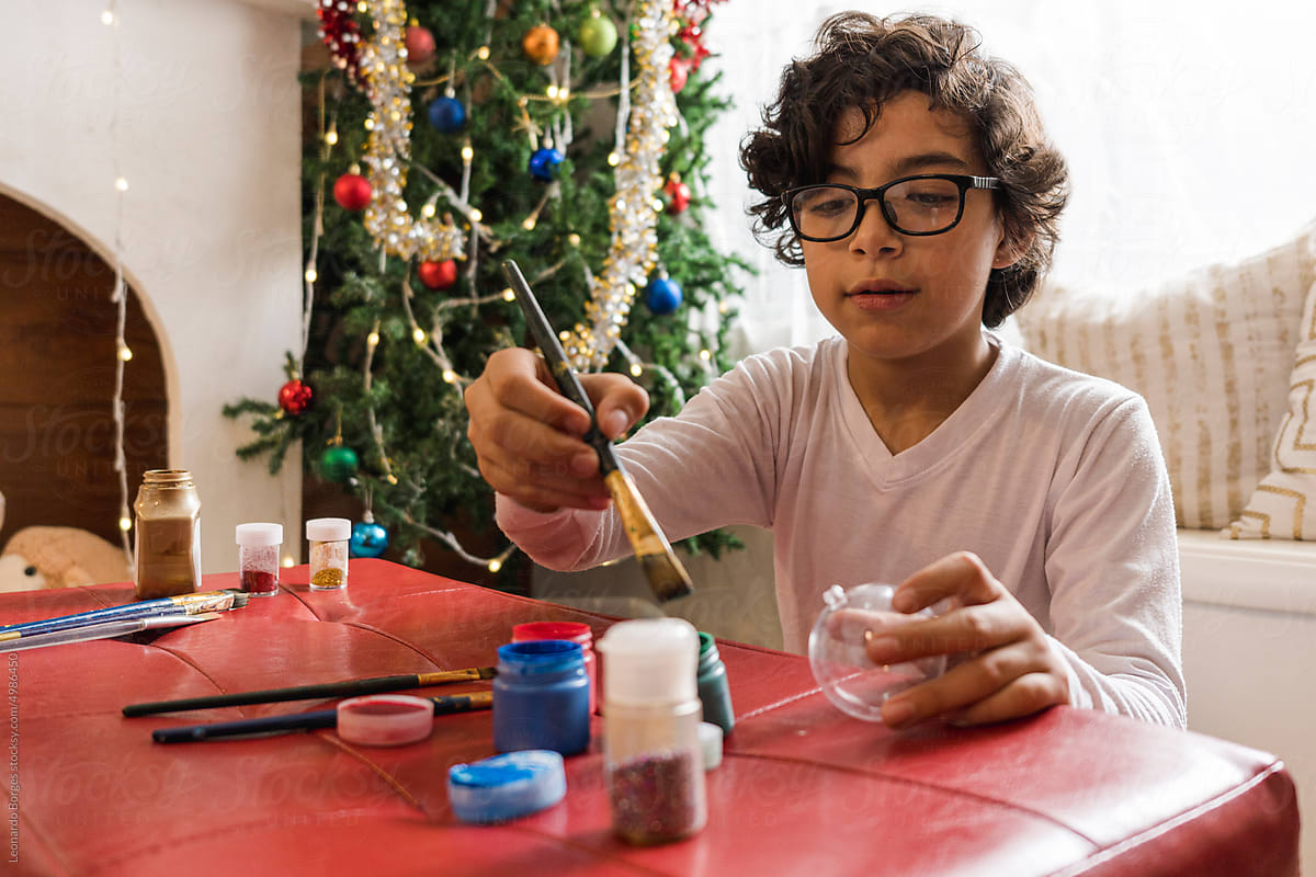 Child painting a Christmas sphere.