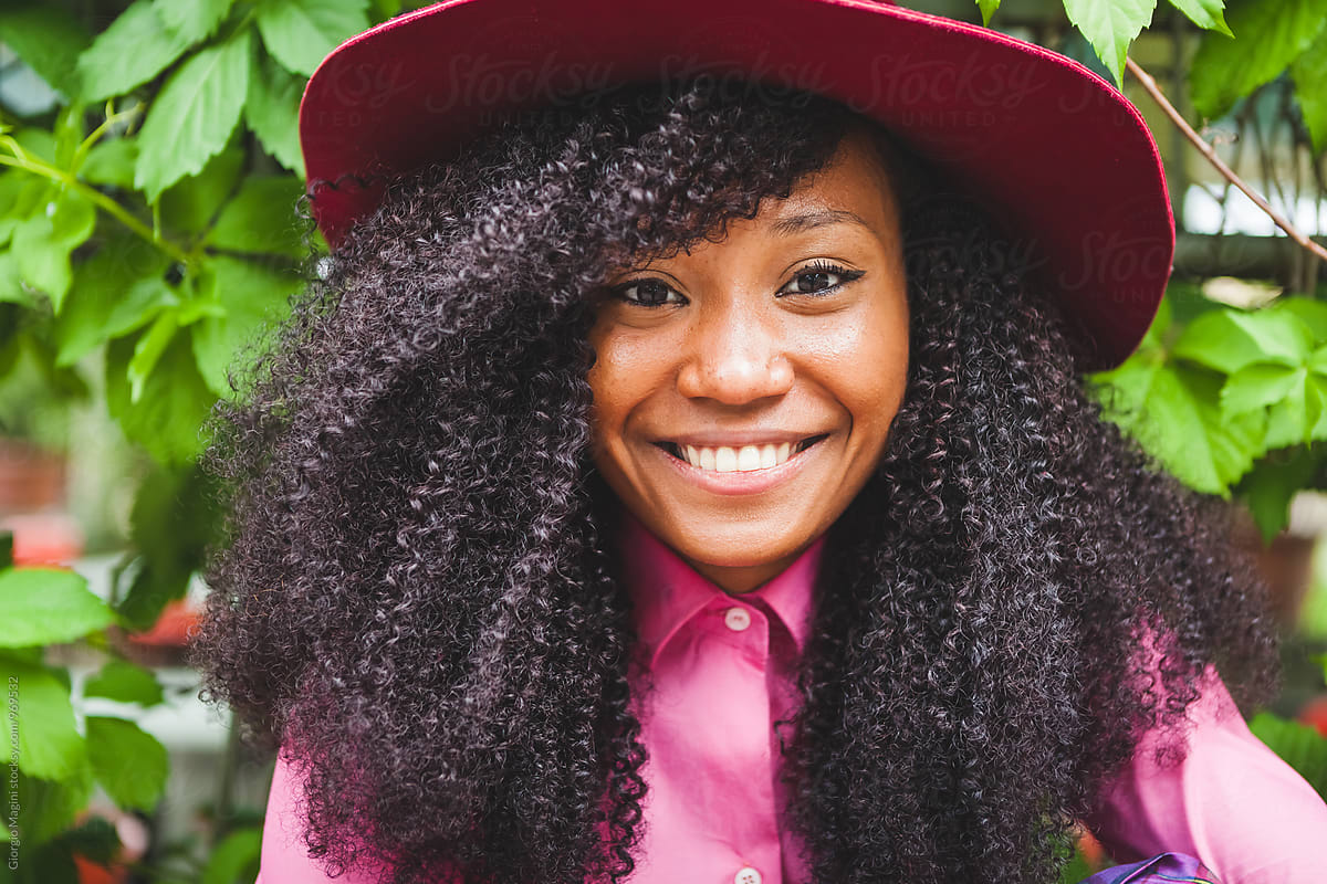 Portrait Of A Smiling Young Woman With Black Curly Hair By Stocksy