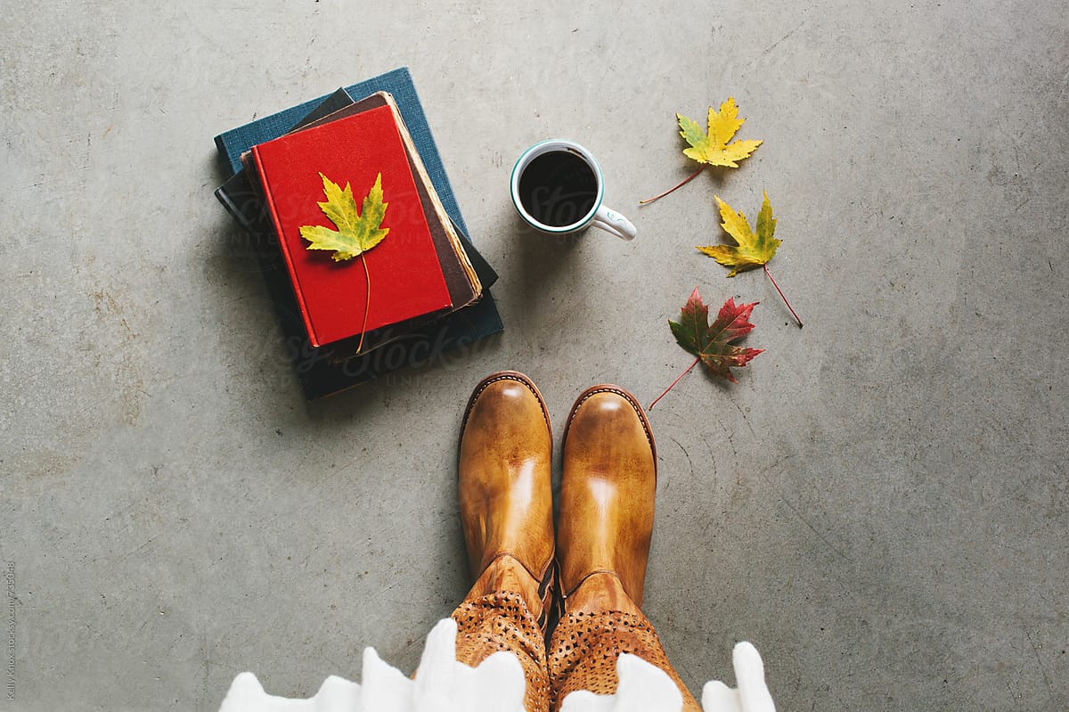 overhead of boots, books, coffee, and autumn leaves