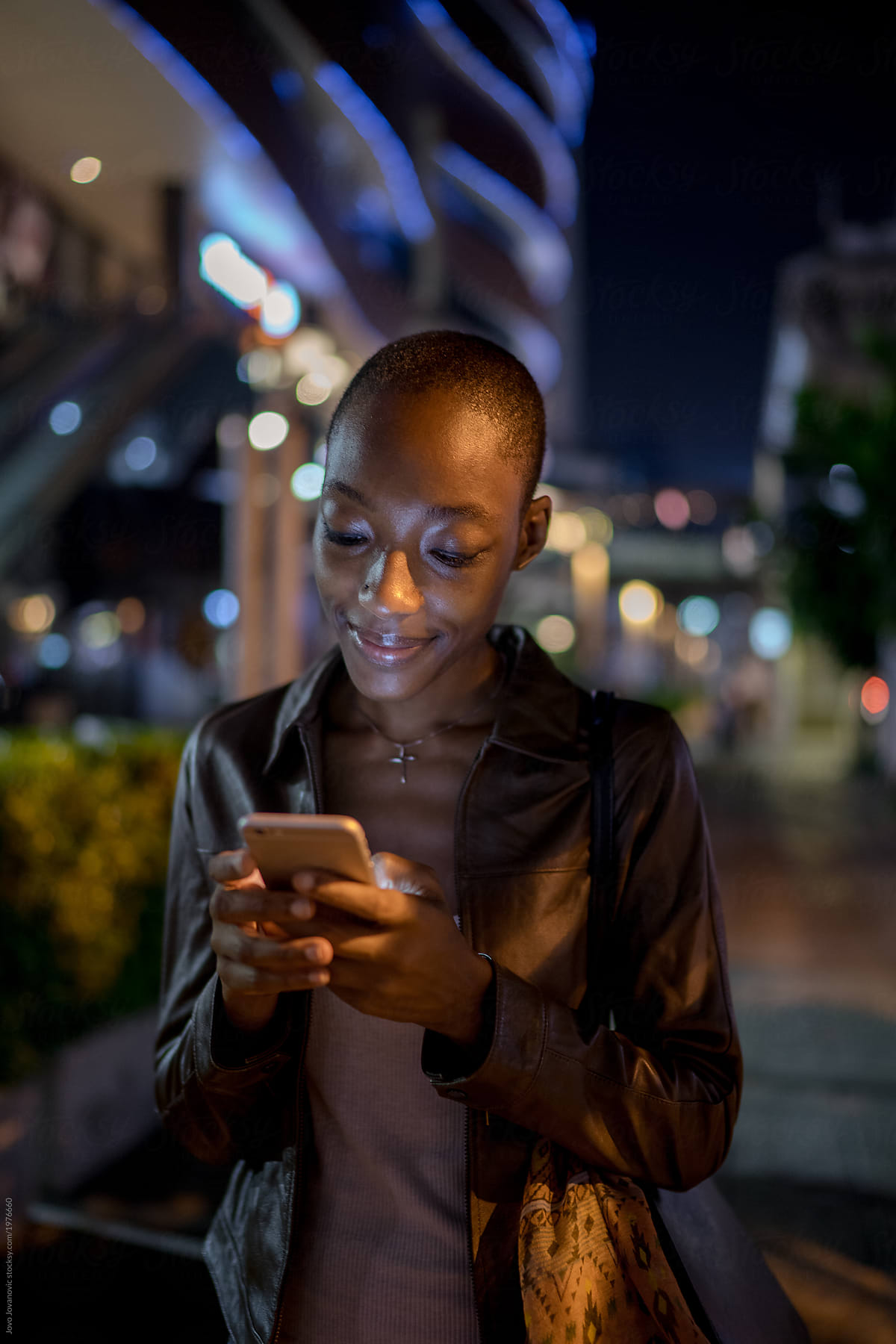 Vertical portrait of a woman using her phone at night