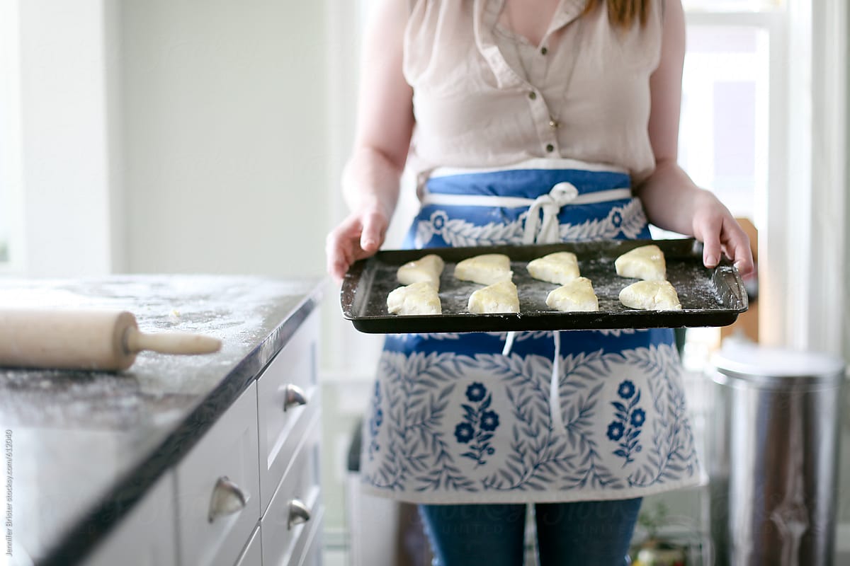 Woman holding pan of unbaked scones
