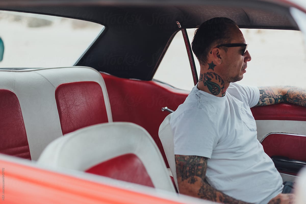 Man With Tattoo Driving an American Vintage Car in the Desert