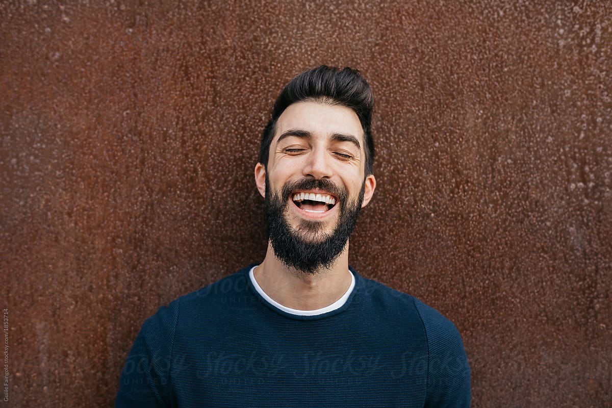 Laughing good-looking man with closed eyes.