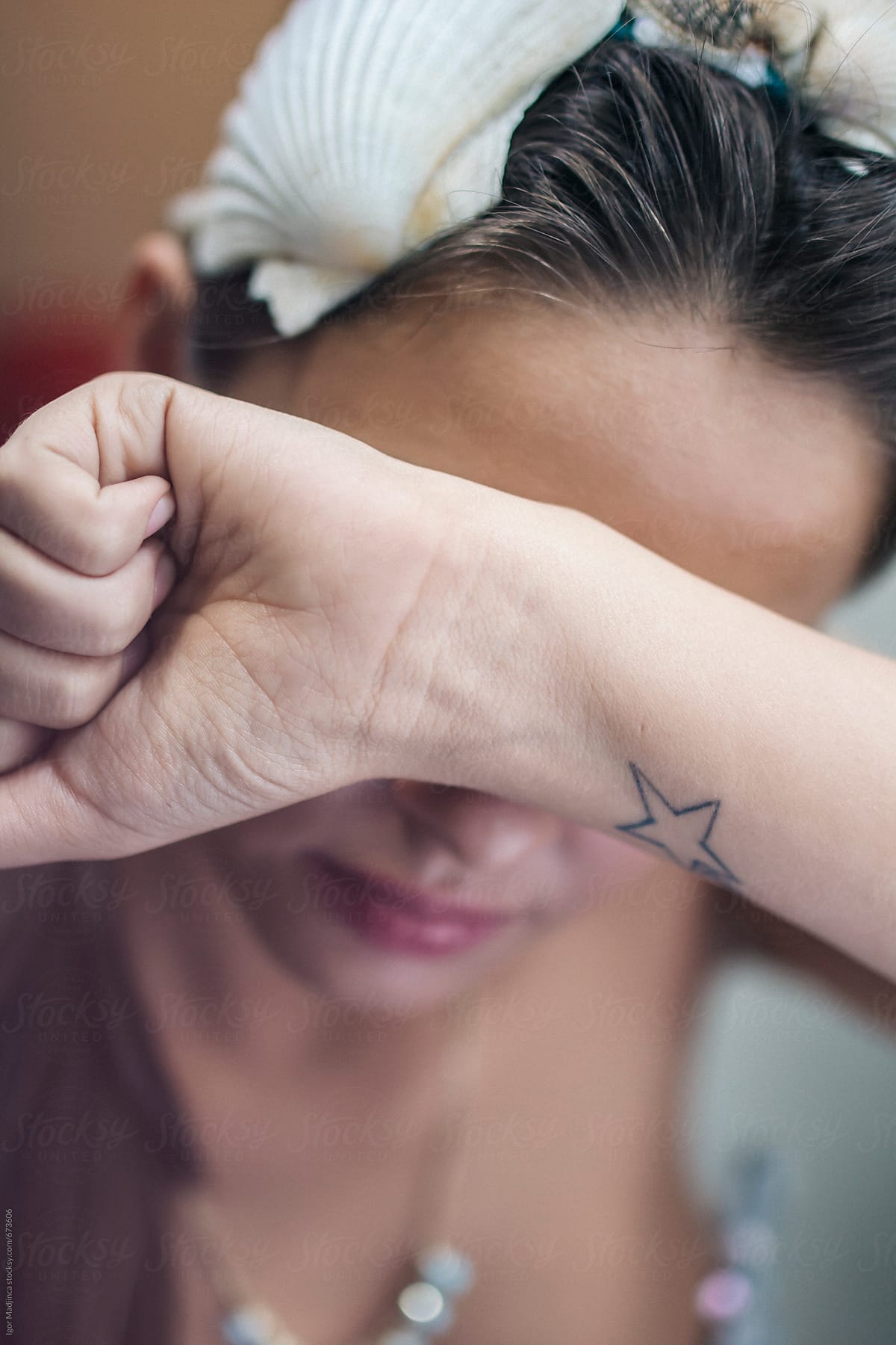girl with a star tattoo  hiding behind her hand, shame
