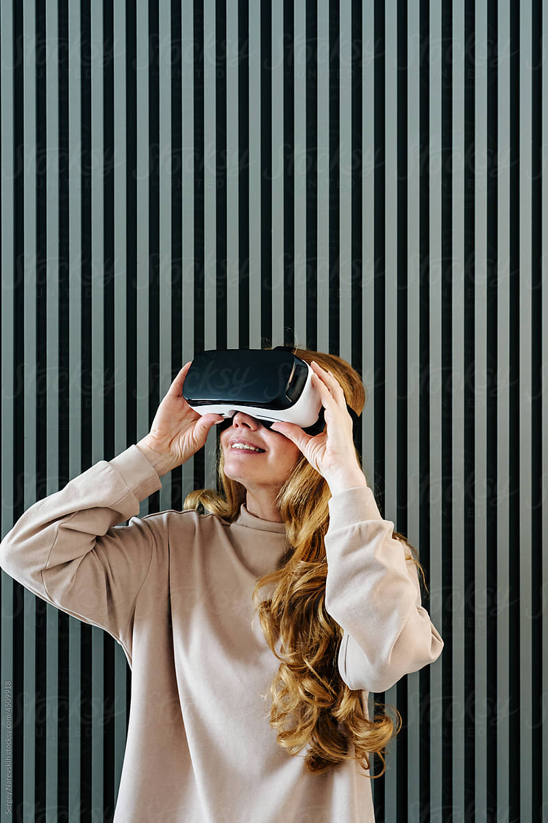 Aged woman in VR glasses near wall