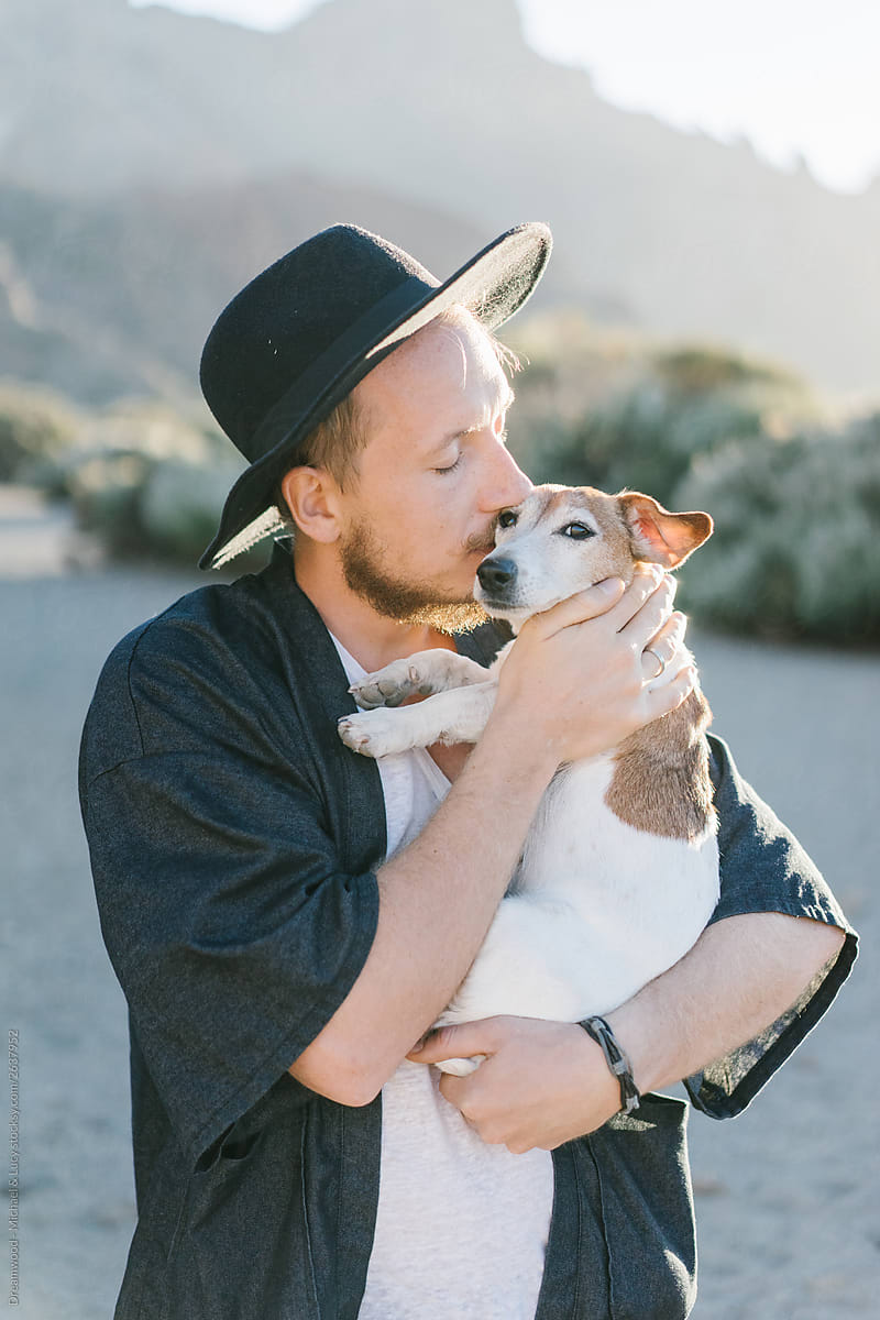 Adult man hugging and kissing dog in desert