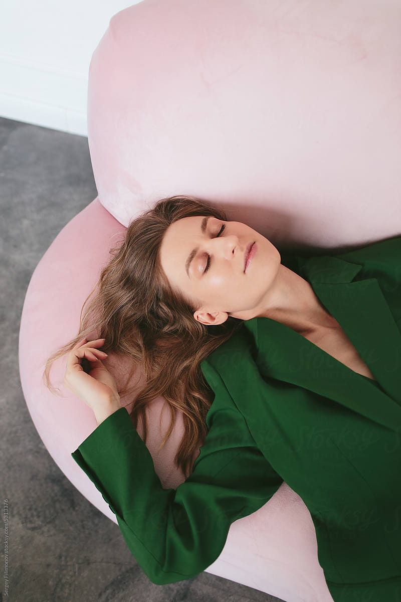 Smiling woman lying on sofa with closed eyes