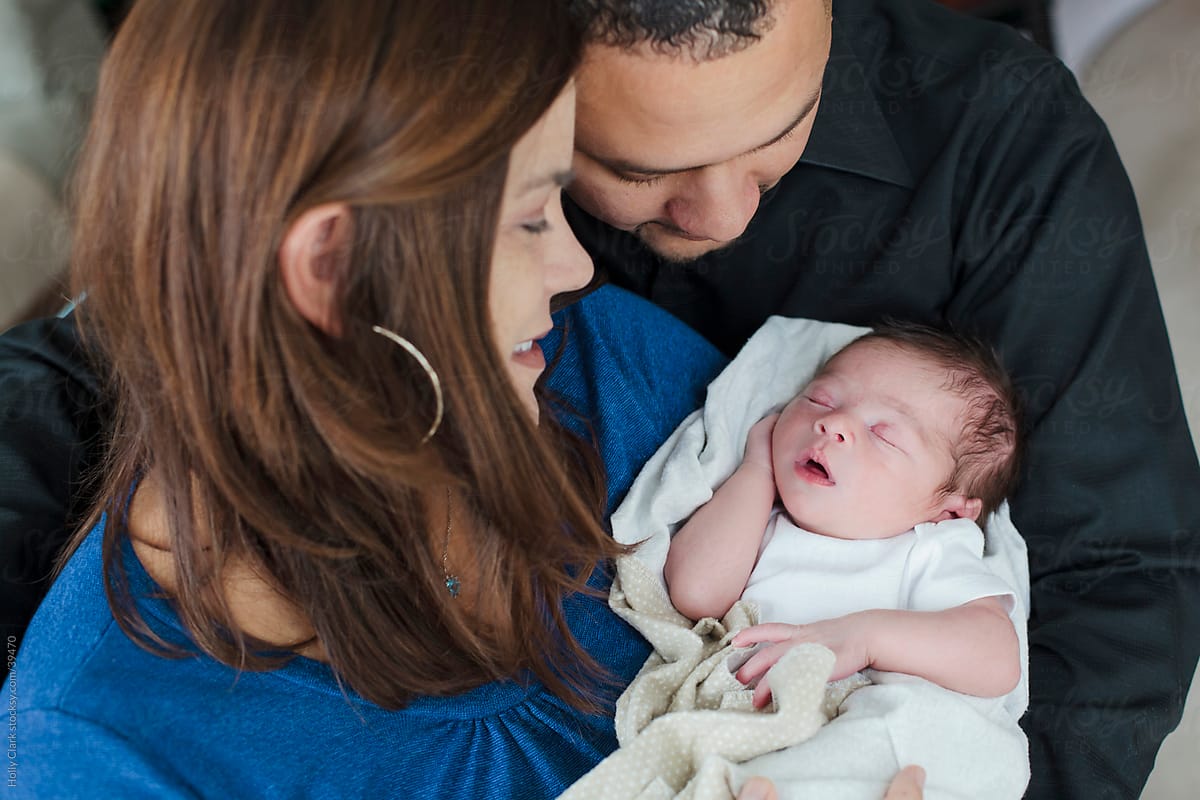 A mixed-race couple embrace their newborn son