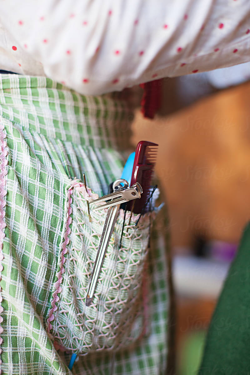 Close up of apron pocket with hairdressing tools and clips