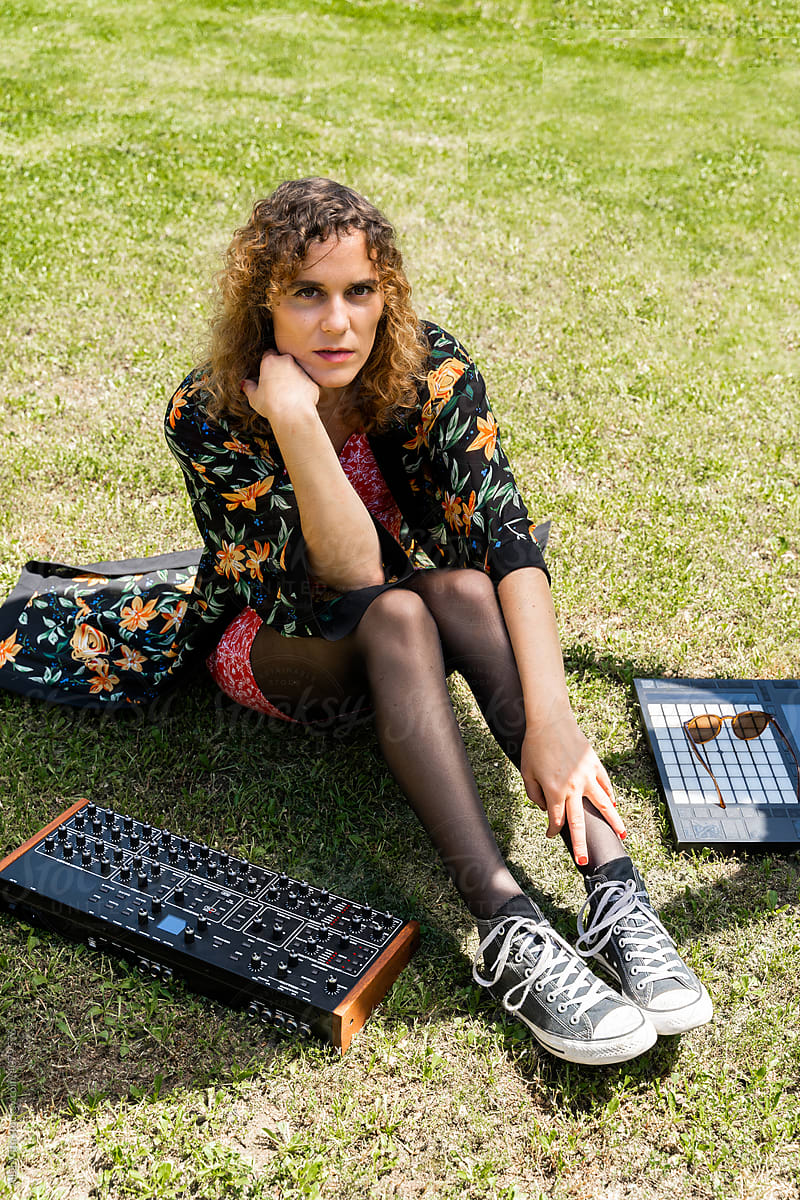 Woman sitting on grass with electronic music devices