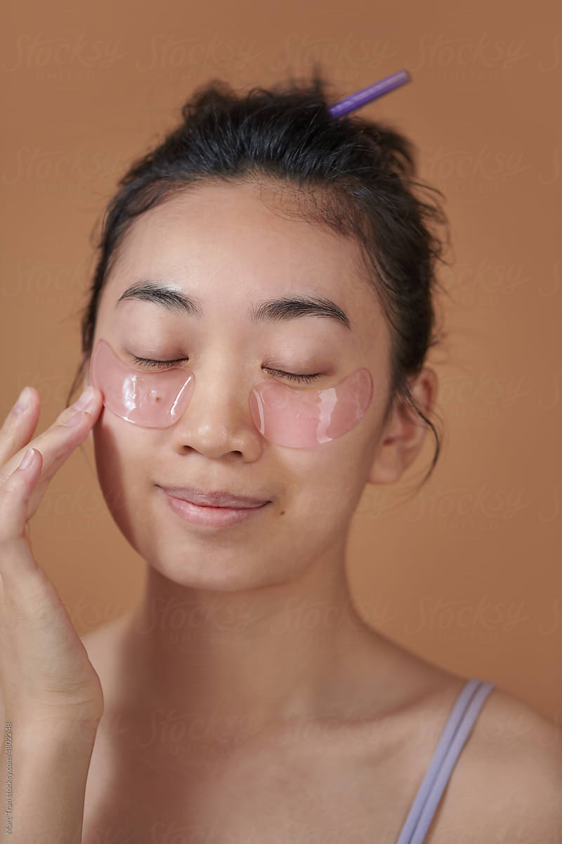 Portrait posing Asian woman applying patches mask under eyes