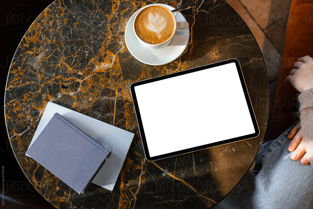 A tablet with white screen on a table in a cafe