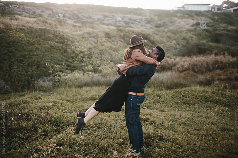 woman lifted off her feet hugging man in a field