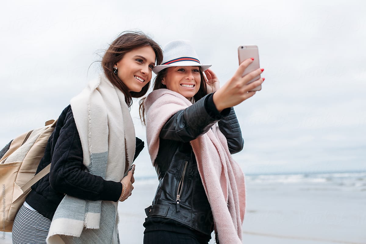 Two tourist girlfriends making selfie on the beach