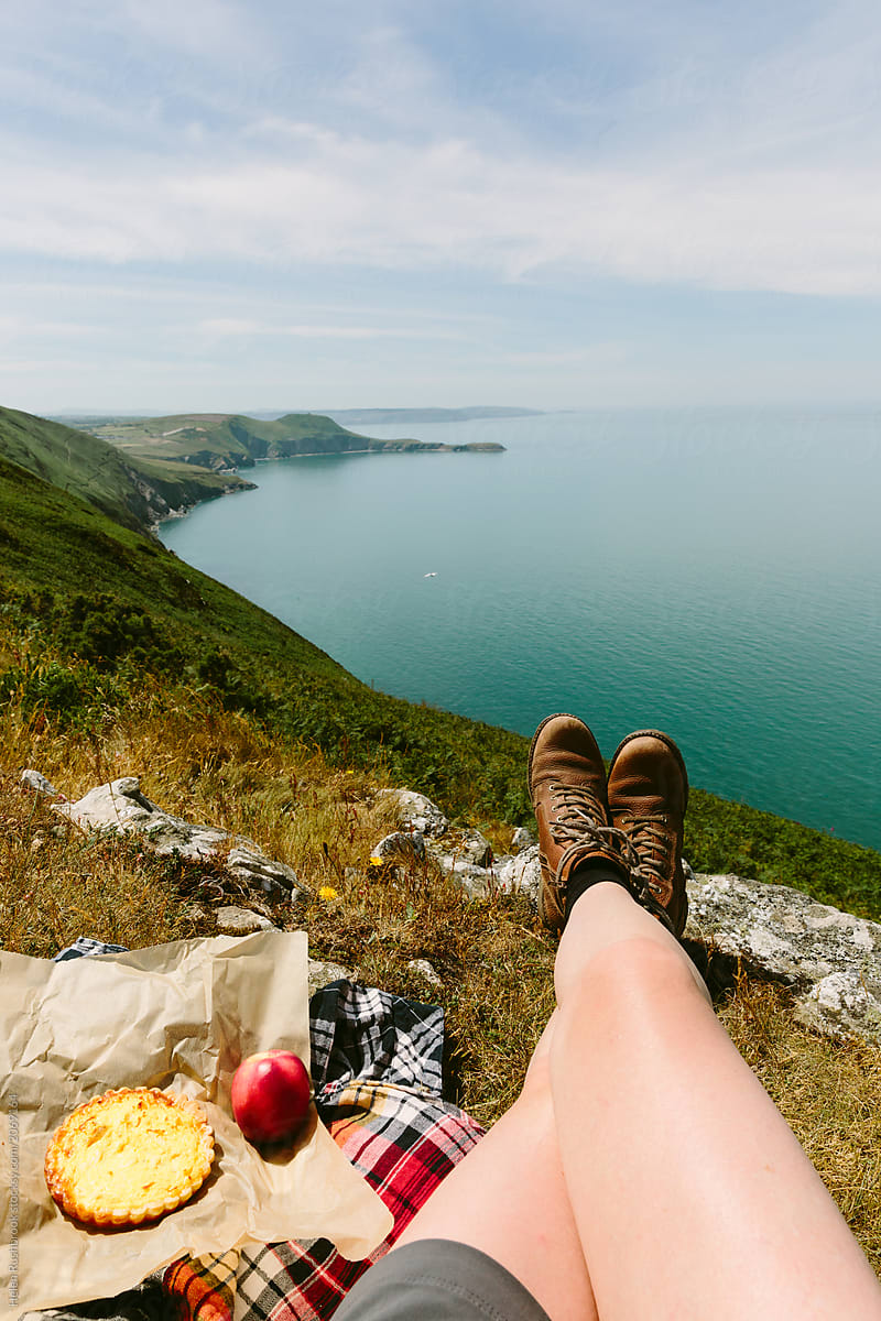 Female hiker sitting high above the ocean with a picnic. Wales. UK.