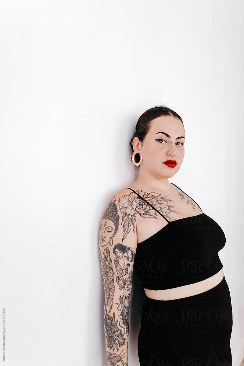 Tattooed curvy woman in black outfit in studio