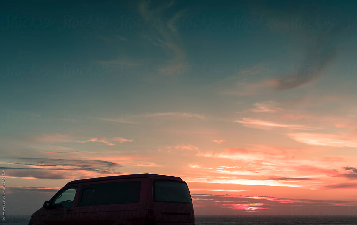 Camper van silhouette near sea with beautiful sunset sky
