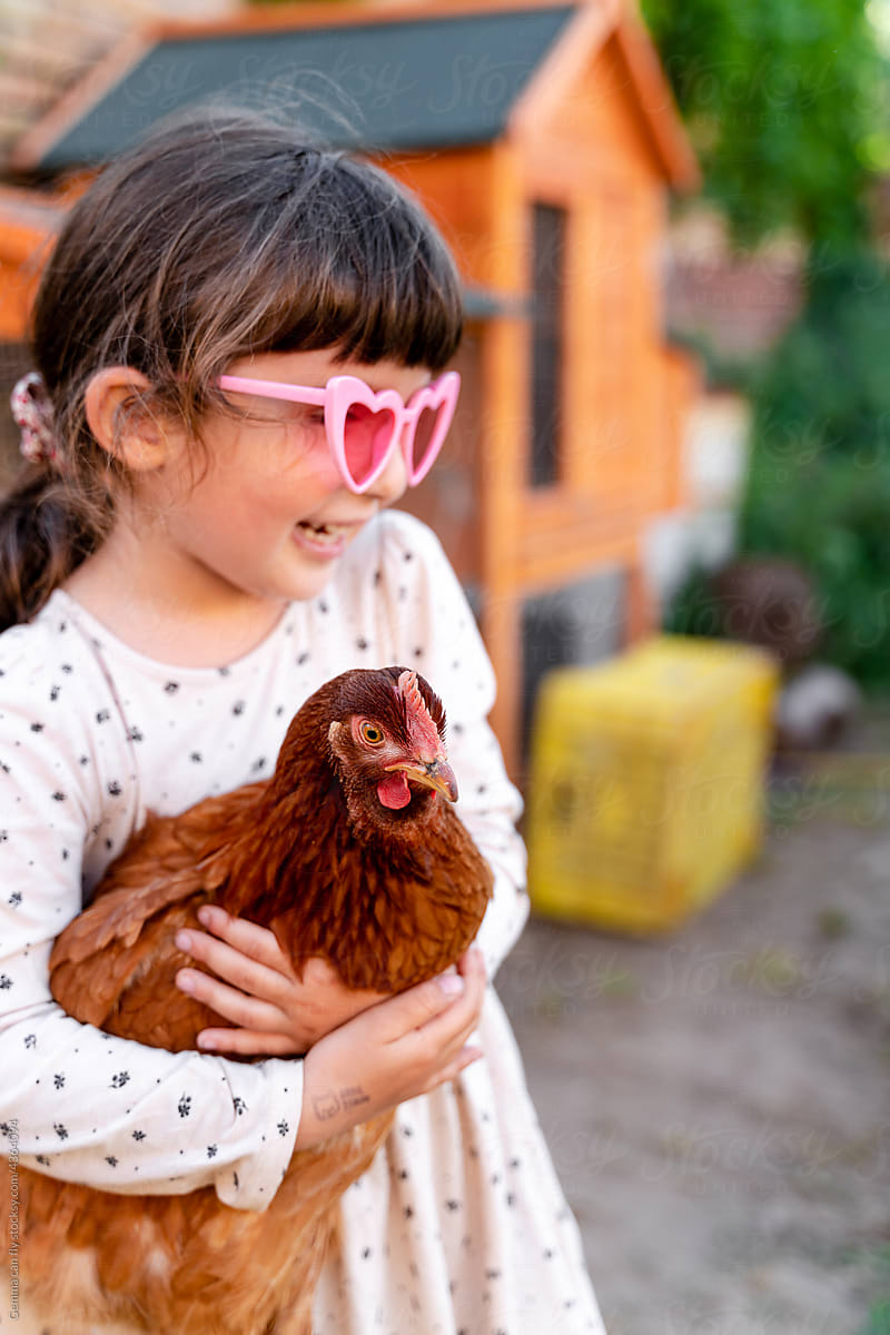 Little girl holding a hen in the orchard. UGC
