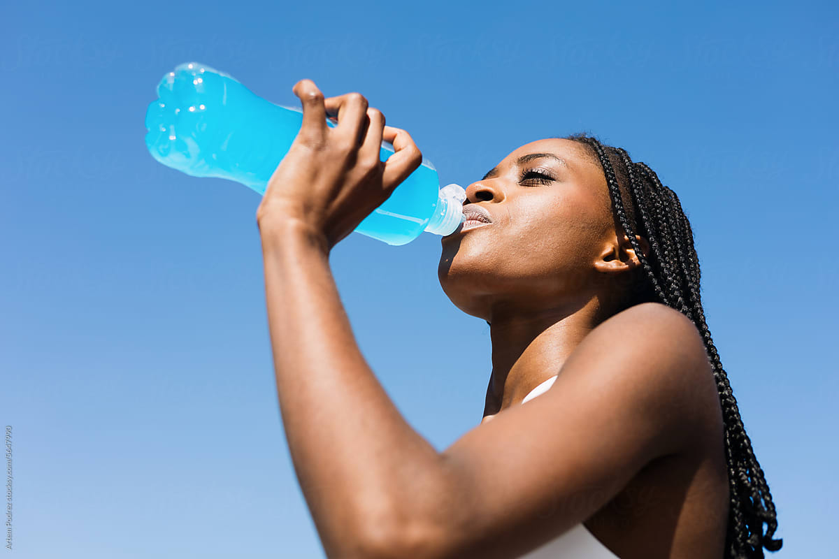a woman drinks sports water after a morning run
