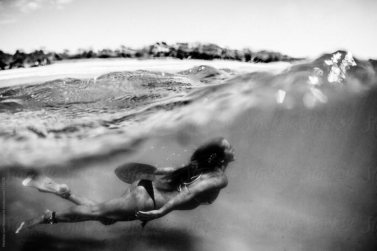 Girl diving under a face of a wave in the ocean.