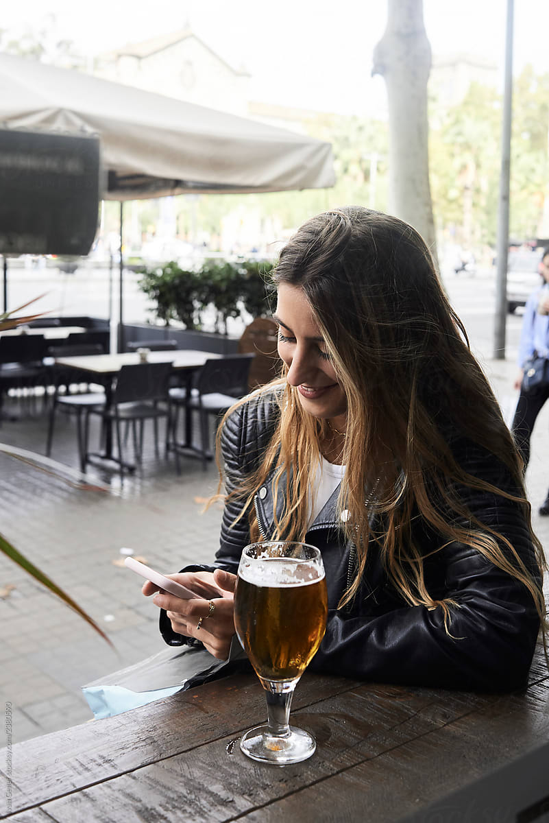 Female millennial smartphone beer terrace.