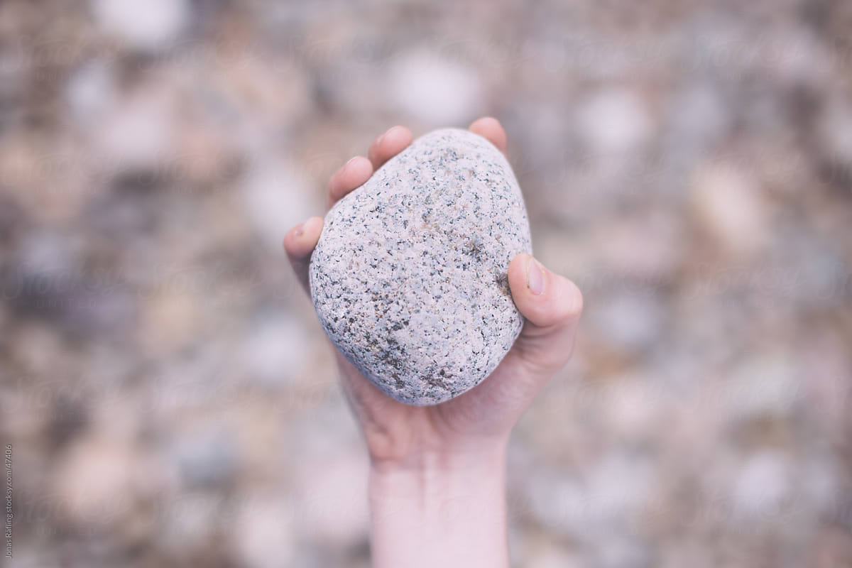 A Hand Holding A Stone Above A Lot Of Stones by Jonas Räfling.