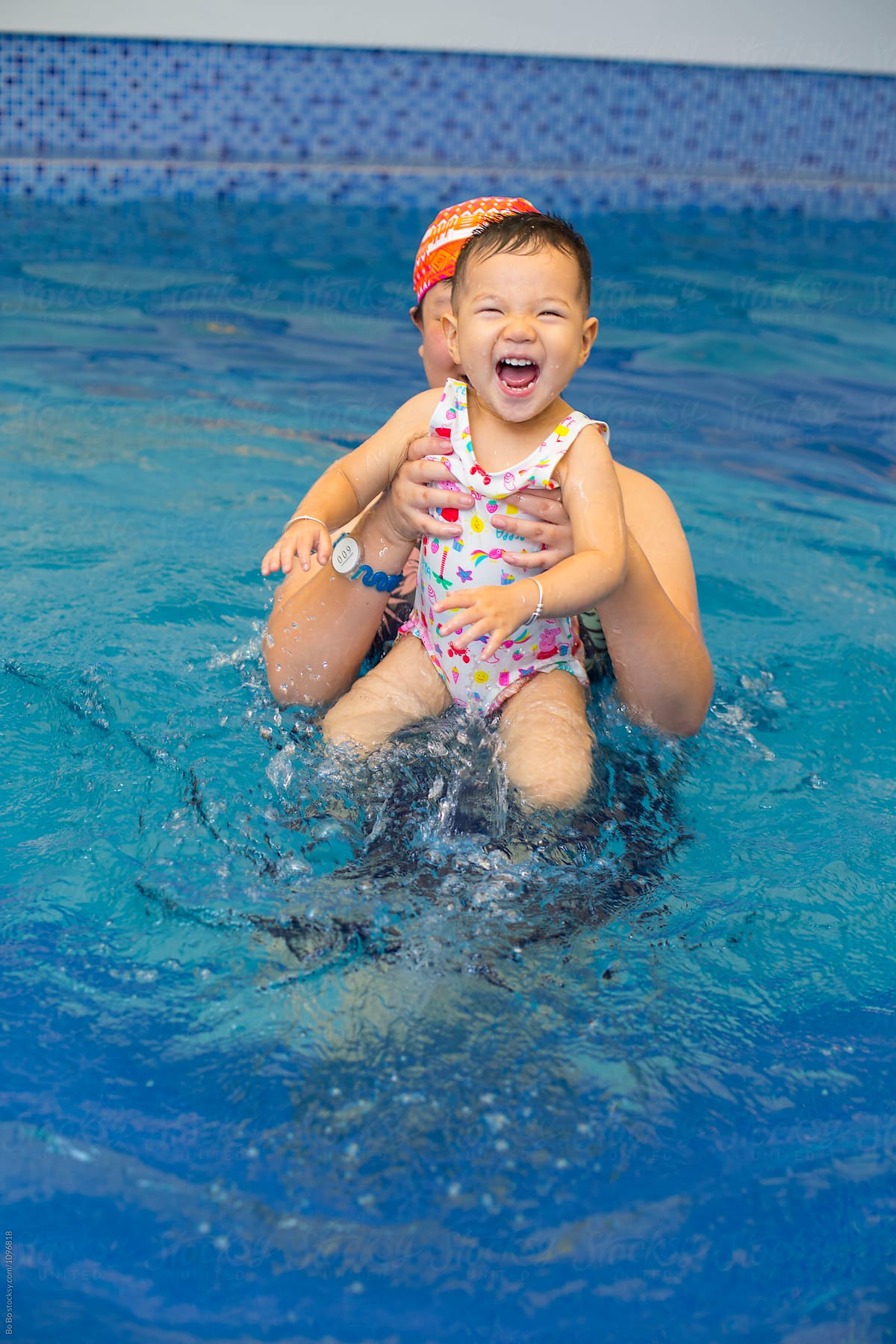 happy woman with her baby girl in swimming pool