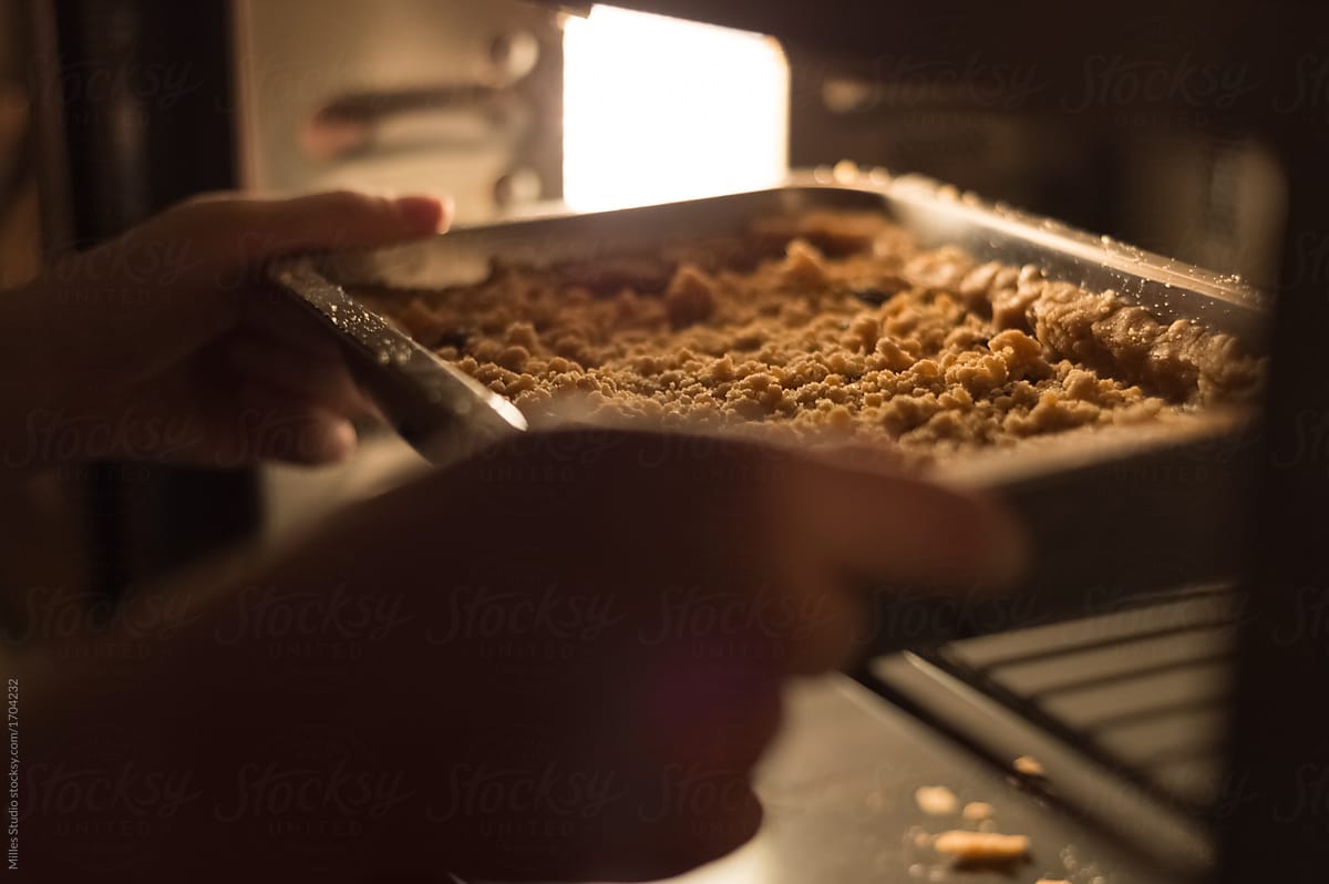 Hands putting pie to oven