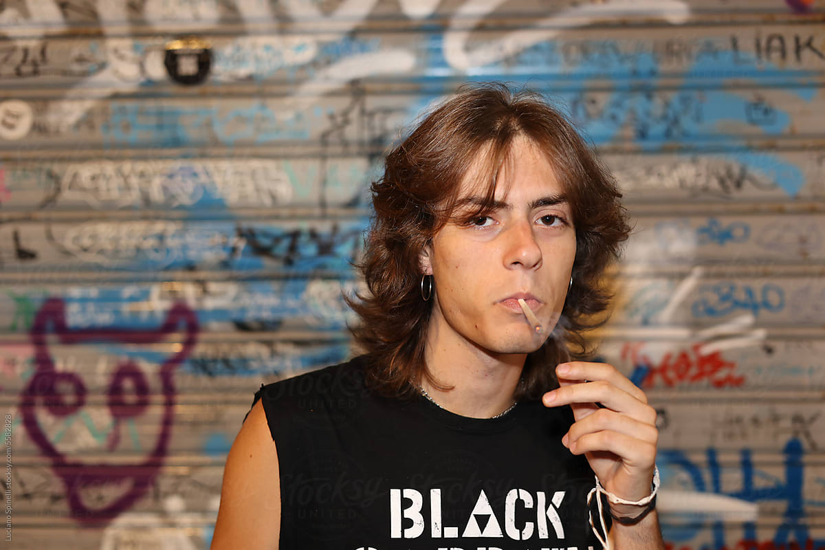 Subversive rock player smoking in front of graffiti roll-up door