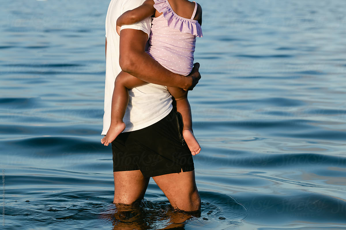 A father protects his daughter in the water