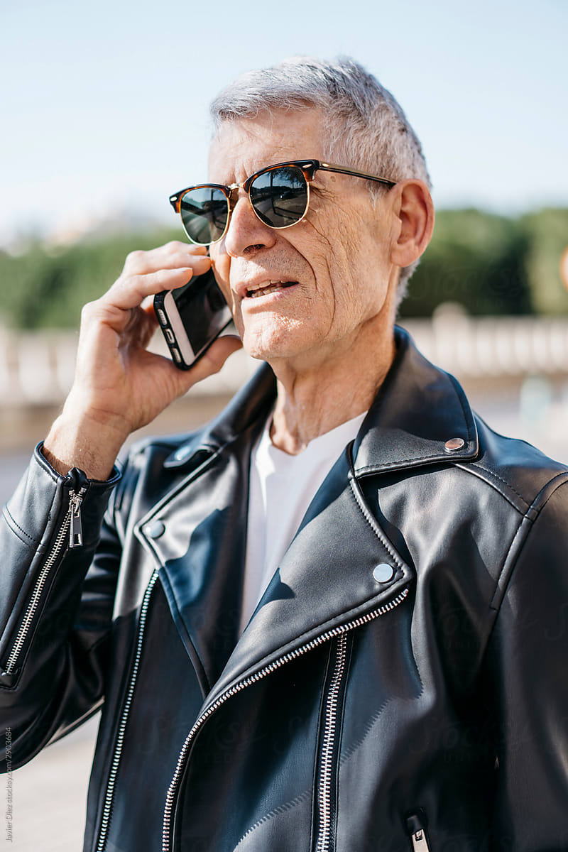 Serious elderly biker talking on smartphone