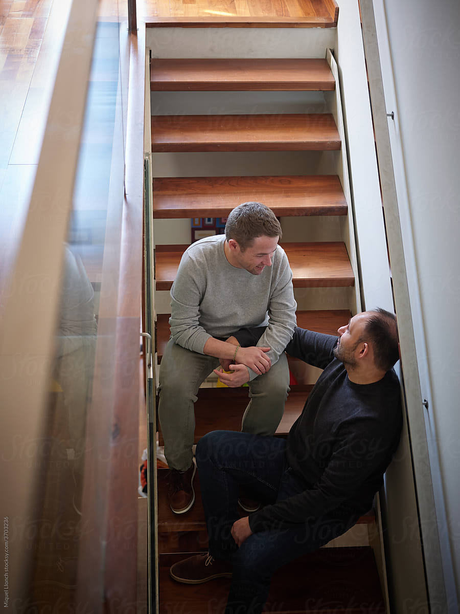 Men couple sitting on stairs and talking.