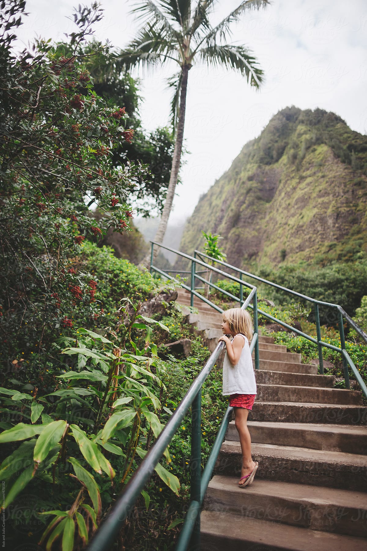 Cute young girl exploring nature in tropical area with many stairs