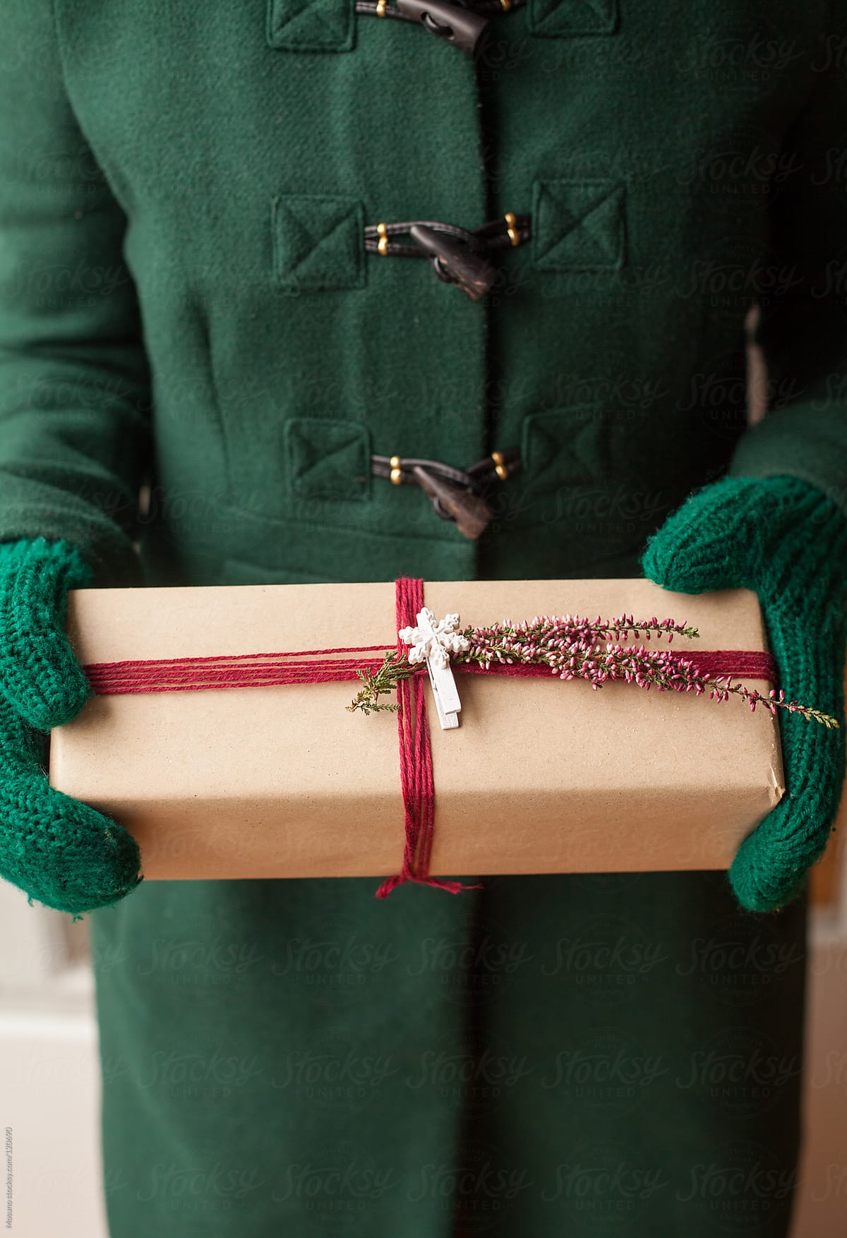 Woman in a Green Coat Holding Christmas Gift