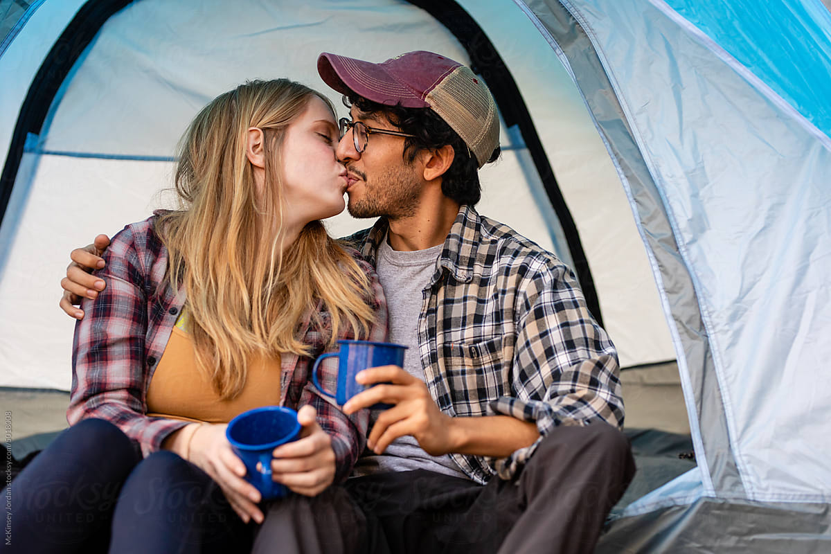 Young Couple Kiss Each Other While In Tent On Camping Trip
