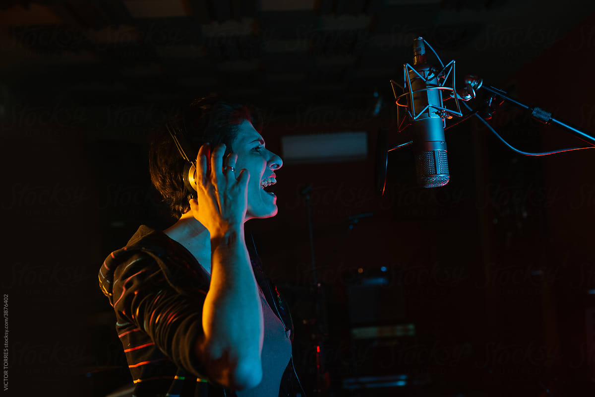 Vocalist singing into professional microphone in recording studio