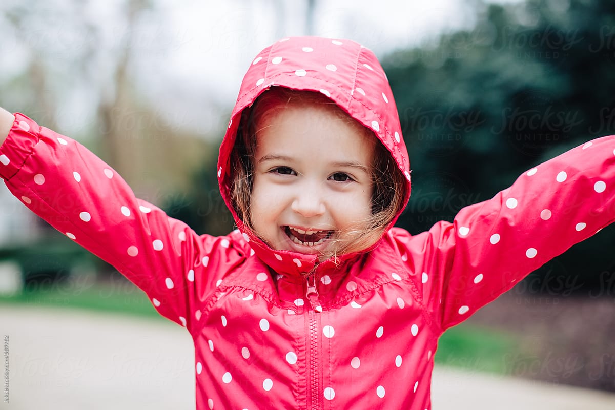 Adorable young girl excited to wear a new rain jacket