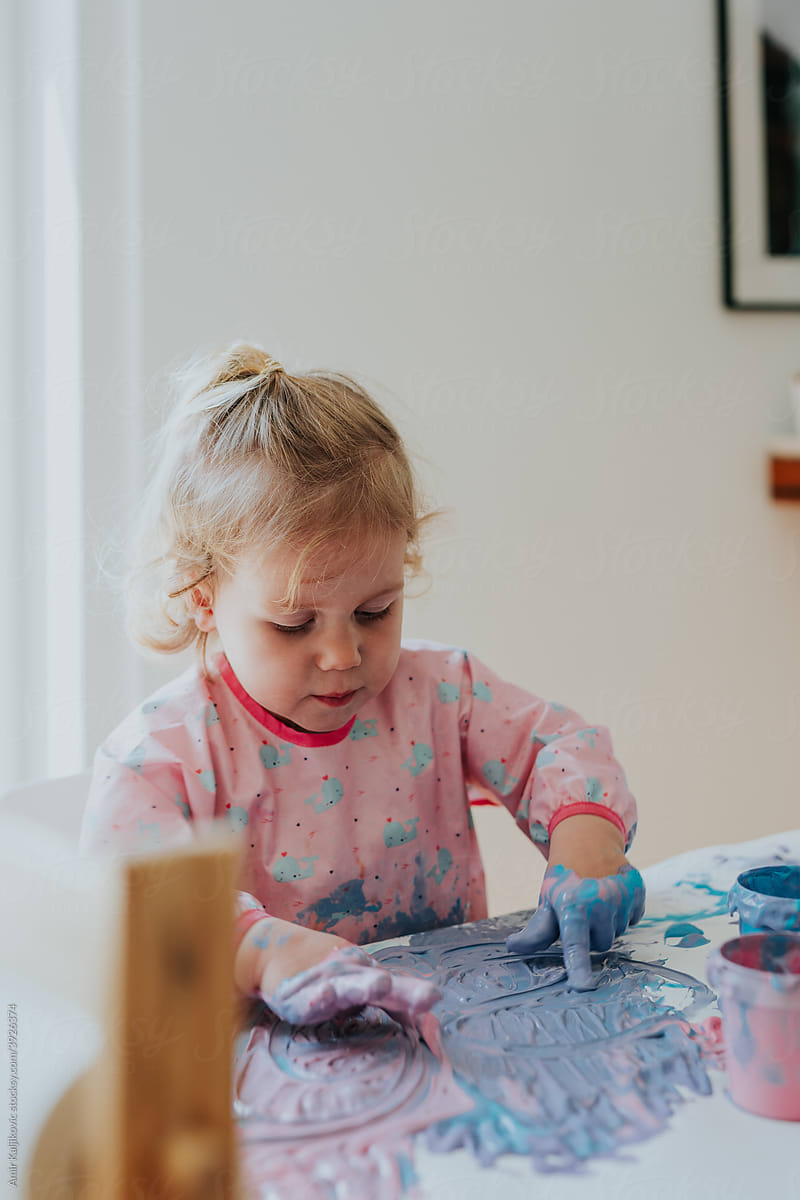 Cute creative artistic little girl doing finger painting